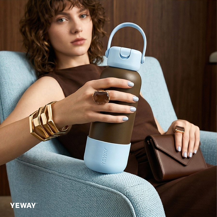 Professional model holding a brown and blue insulated water bottle with a square-round handle lid, highlighting the premium finish and portability for corporate use.